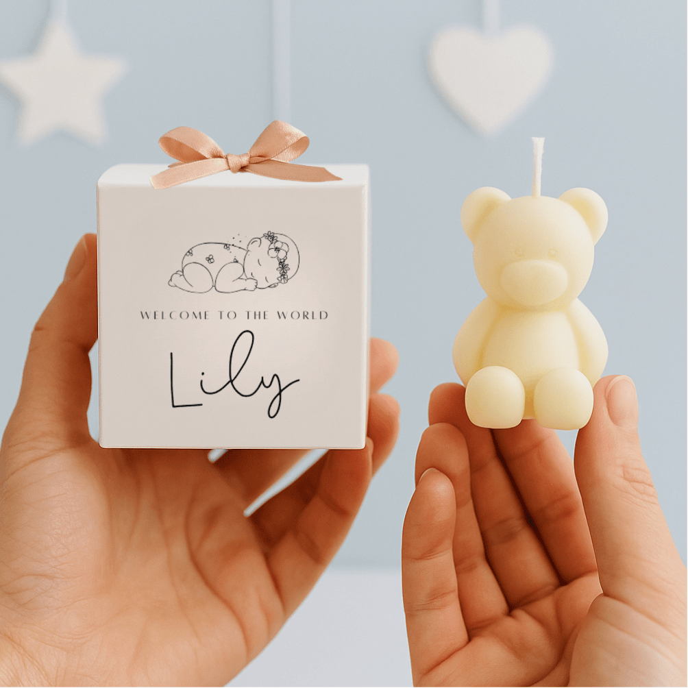 Small bear-shaped candle held by a hand with a matching gift box labeled 'Lily' against a light blue background.