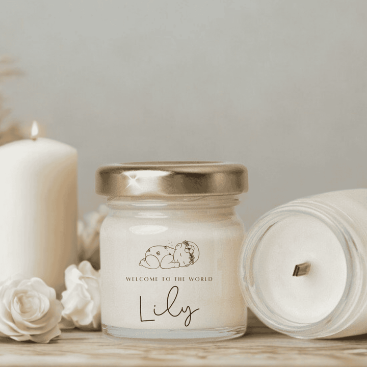 Jar of candle with 'Welcome to the World Lily' text, surrounded by white flowers on a light background