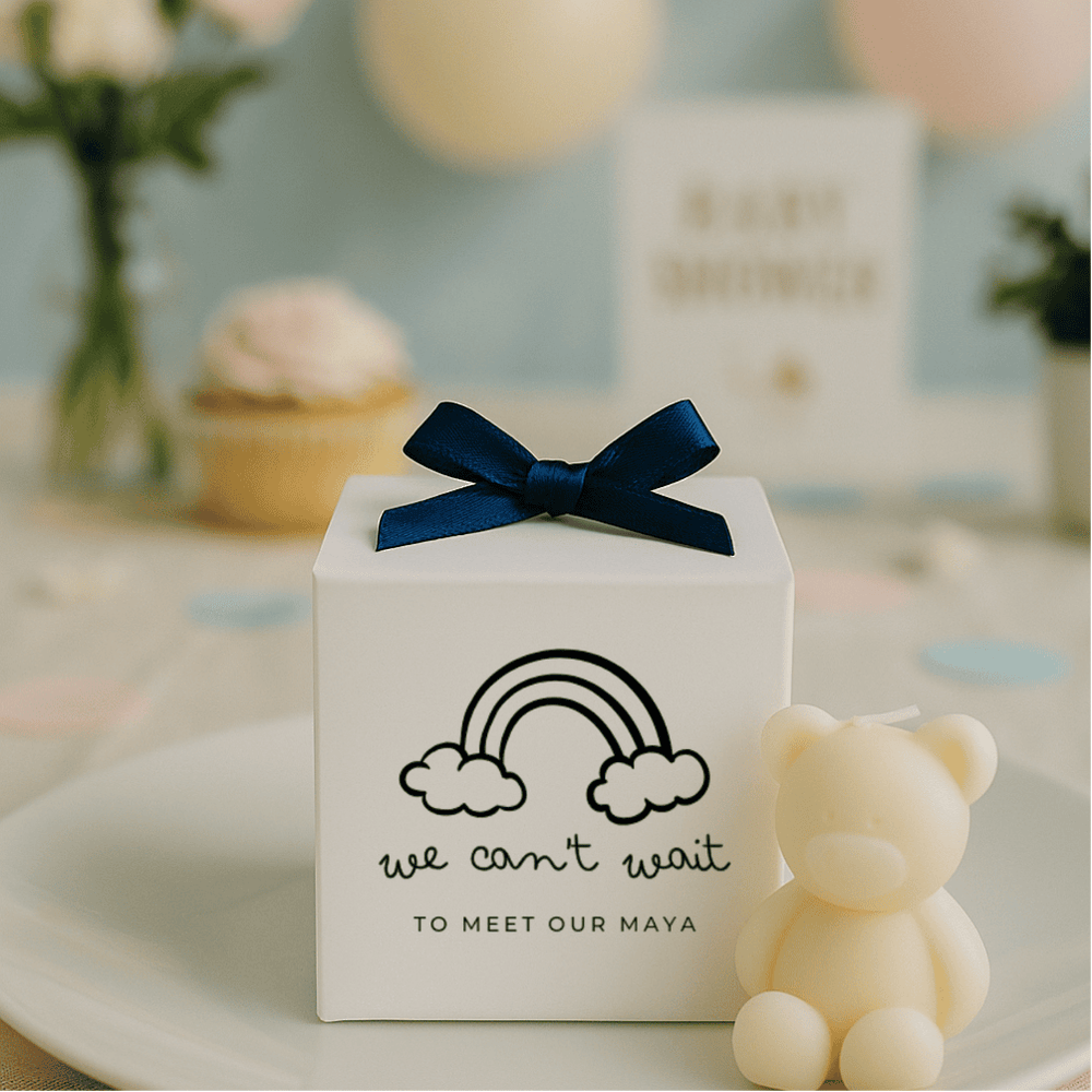 White gift box with navy blue bow and personalized message, next to a small teddy bear on a decorative surface.