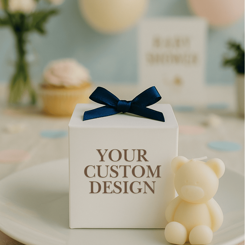 White gift box with a blue bow and 'YOUR CUSTOM DESIGN' text, next to a small teddy bear on a decorative surface.